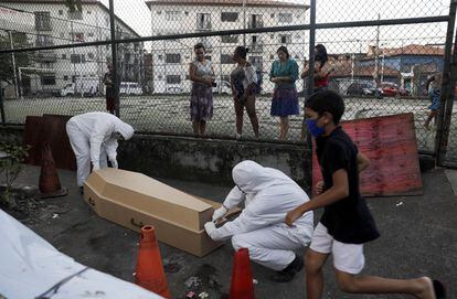 Funcionários de uma funerária levam de uma favela no Rio de Janeiro o cadáver que, segundo a vizinhança, levou 30 horas para ser recolhido.