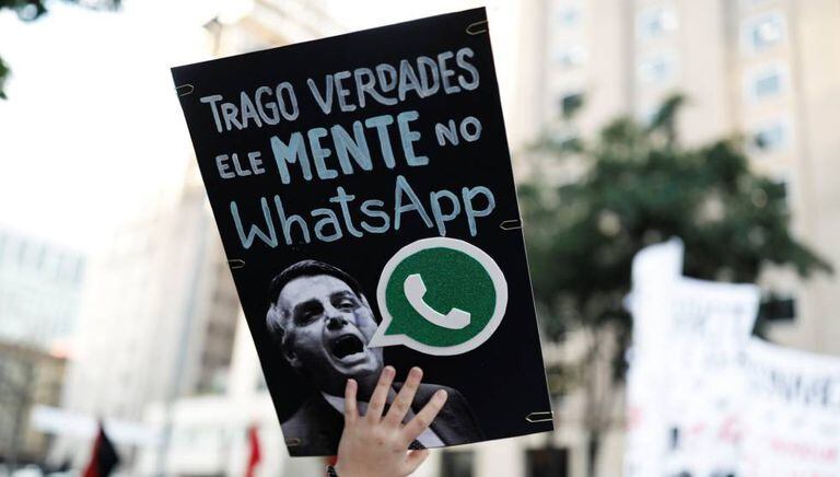 A woman holds a sign with the image of presidential candidate Jair Bolsonaro that reads