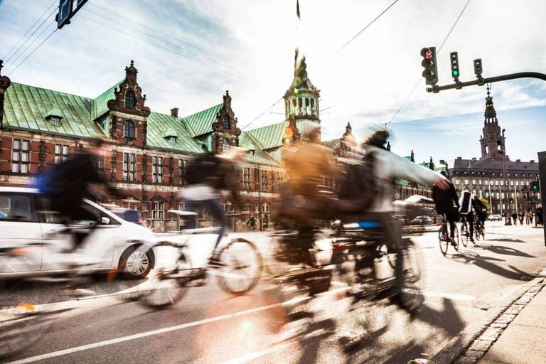 Ciclistas em Copenhague, com o edifício da Bolsa ao fundo