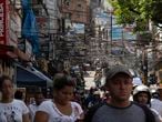 Residents walk in Rio de Janeiro's Rocinha slum in Brazil, Monday, March 16, 2020. Since the outbreak of the new coronavirus, nations have begun imposing travel restrictions and closing their borders to contain the pandemic's spread. The latest attempt to impose controls is a smaller territory: the hillside slum of Rocinha in Rio de Janeiro. (AP Photo/Silvia Izquierdo)
