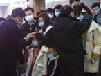 Los miembros del personal verifican la temperatura corporal de los pasajeros que llegan del tren de Wuhan a Hangzhou, en la estación de trenes de Hangzhou, antes del Año Nuevo Lunar chino en la provincia de Zhejiang, el 23 de enero.