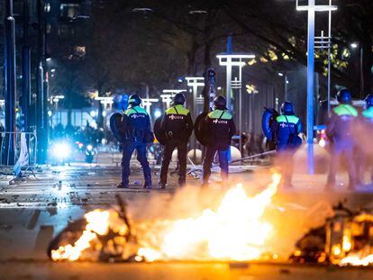 Varios policías se interponen entre los manifestantes y una motocicleta quemada en Róterdam, el viernes.