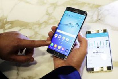 Um homem sujeita o novo Samsung Galaxy S6 Edge Plus. Sobre a mesa, o Note 5