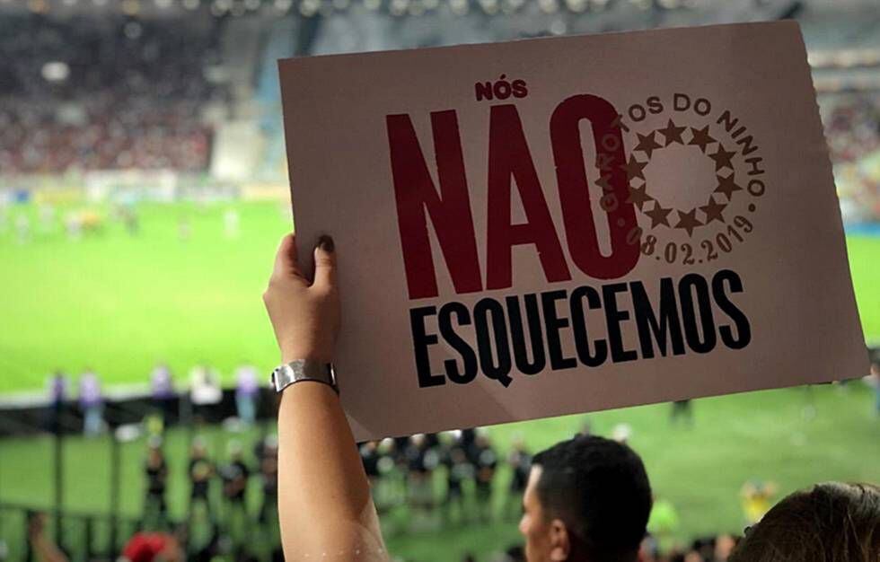 Torcedores do Flamengo mostram cartaz no estádio em referência ao incêndio.