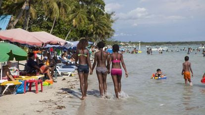 Três jovens passeiam pela praia de Boca Chica.