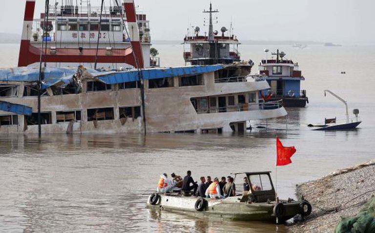 Trabalhadores sobre o barco que naufragou, depois de endireitá-lo.