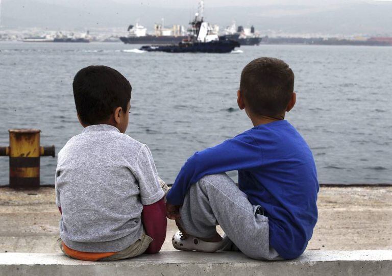 Dois meninos refugiados observam o mar, na Grécia.