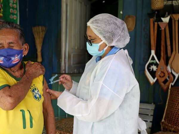 Raimundo Araujo, 90, receives the AstraZeneca/Oxford vaccine for the coronavirus disease (COVID-19) from a municipal health worker in the Sustainable Development Reserve of Tupe in the Negro river banks in Manaus, Brazil, February 9, 2021. Picture taken February 9, 2021. REUTERS/Bruno Kelly