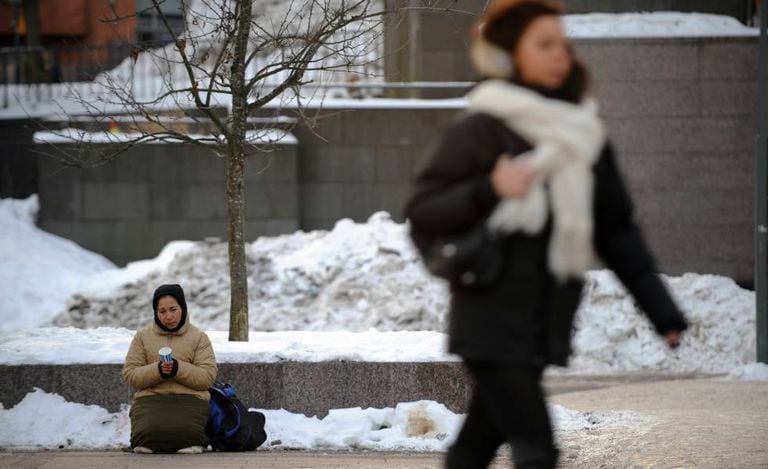 Mulher pede dinheiro em uma rua de Helsinki, em janeiro de 2010.