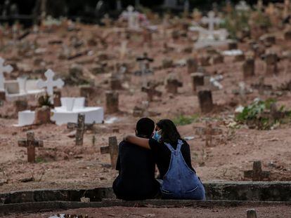 Familiares de vítima de covid-19, sepultada no Rio de Janeiro, se apoiam em cemitério em imagem de abril de 2021