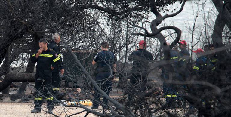 Bombeiros junto aos cadáveres carbonizados em Mati.