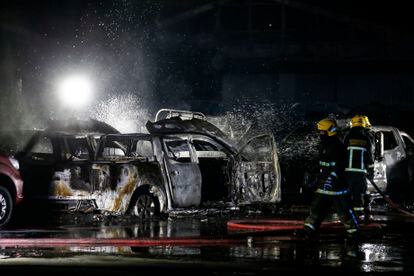 Três bombeiros apagam um incêndio provocado durante os protestos da noite de 14 de julho em Santiago.
