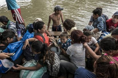 Mulheres e crianças sobem numa embarcação para cruzar o rio Suchiate.