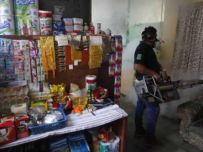 Funcionário do Ministério da Saúde de El Salvador fumega uma casa.