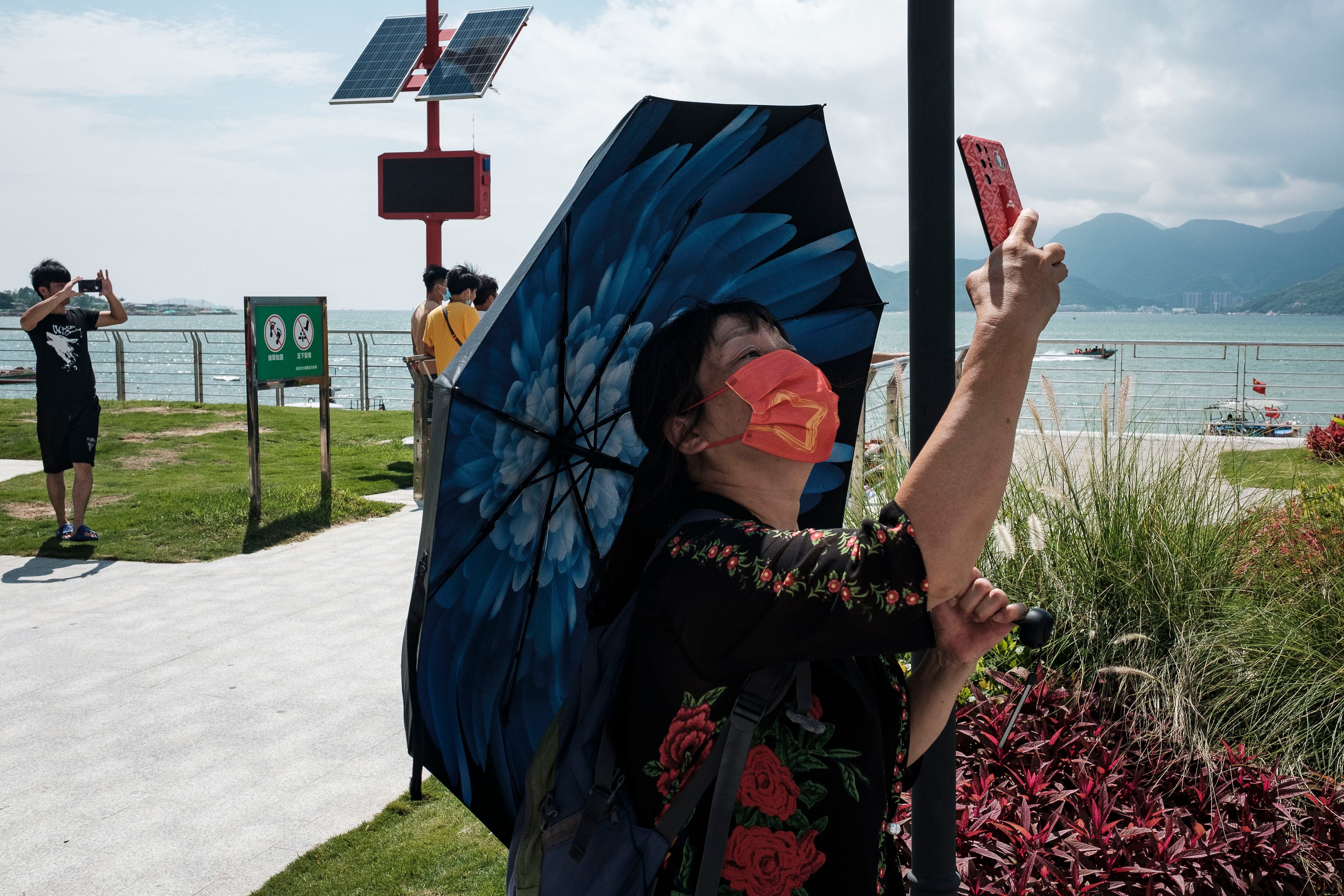 Uma chinesa com máscara facial de proteção faz uma foto com o celular.