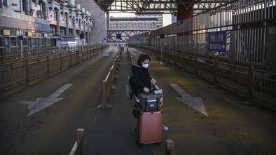 Mulher em um estacionamento de táxi vazio uma estação de trem na região oeste de Pequim.