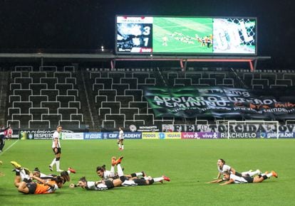 Jogadoras do Corinthians comemoram título brasileiro em 2020. Ao fundo, faixa de apoio ao futebol feminino