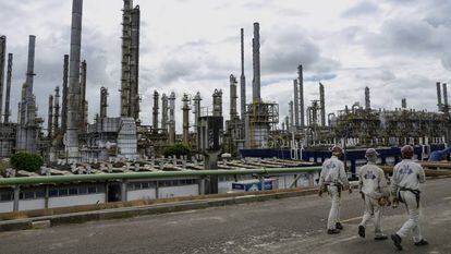 Trabalhadores passeiam diante da indústria petroquímica em Camaçari, no Brasil