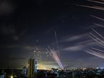 In the background the Israeli Iron Dome missile defence system (L) intercepts rockets (R) fired by the Hamas movement towards southern Israel from Beit Lahia in the northern Gaza Strip, and on foreground tens of other intercepts rockets (RR) fired by the Hamas while the Iron Dome is busy with the first rockets, as seen in the sky above the Gaza Strip overnight on May 16, 2021. - Israel pummelled the Gaza Strip with air strikes, killing 10 members of an extended family and demolishing a building housing international media outlets, as Palestinian militants fired back barrages of rockets. (Photo by ANAS BABA / AFP)