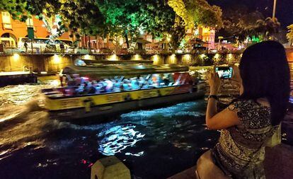 Uma turista fotografando um cruzeiro fluvial em Malaca (Malásia).