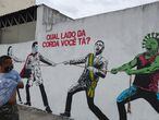 A man looks to a graffiti with Brazilian President Jair Bolsonaro and a person depicting the coronavirus pulling a rope against health workers in Sao Paulo, Brazil, June 10, 2020. The graffiti reads:"Which side are you?". REUTERS/Amanda Perobelli