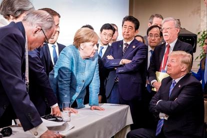 Donald Trump escuta Angela Merkel e Emmanuel Macron, próximo a Shinzo Abe (de pé, no centro) e assessores, durante encontro do G7 em Charlevoix (Canadá), em 2018.