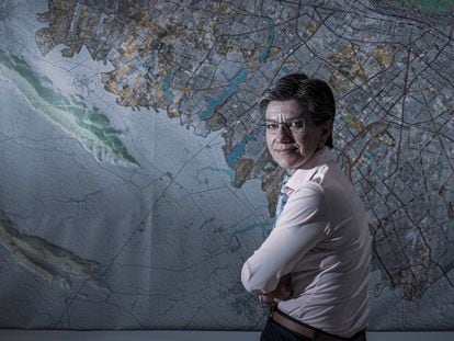 La alcaldesa de Bogotá, Claudia López, posa en su despacho junto a un mapa de la capital de Colombia.