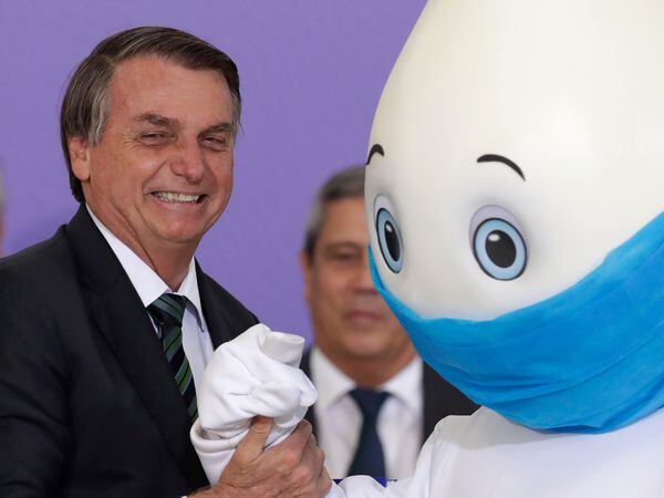 Brazilan President Jair Bolsonaro poses for photos with the mascot of his nation's vaccination campaign, named "Ze Gotinha," or Joseph Droplet, during a ceremony to present the National Vaccination Plan Against COVID-19 at Planalto presidential palace in Brasilia, Brazil, Wednesday, Dec. 16, 2020. (AP Photo/Eraldo Peres)