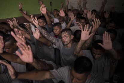 Antigos membros de gangues, presos na cadeia de Gotera, levantam as mãos durante o culto religioso