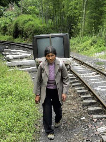 Uma mulher carrega uma televisão em Sichuan.