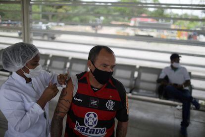 Um homem recebe uma dose da vacina da Pfizer contra a covid-19 numa estação de ônibus do Rio de Janeiro.