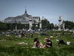 TOPSHOT - People enjoy a sunny day on a loan near the Grand Palais and the Pont Alexandre III bridge in Paris on May 20, 2020 as France partially lifted restrictions to prevent the spread of the COVID-19 disease caused by the novel coronavirus. (Photo by Philippe LOPEZ / AFP)