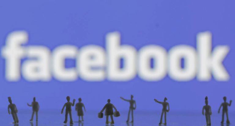 Bonecos feitos em impressora 3D na frente de logo do Facebook.