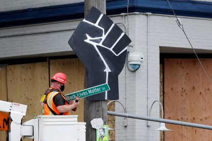 Funcionário retira placa "Black Lives Matter St." em Seattle, EUA.