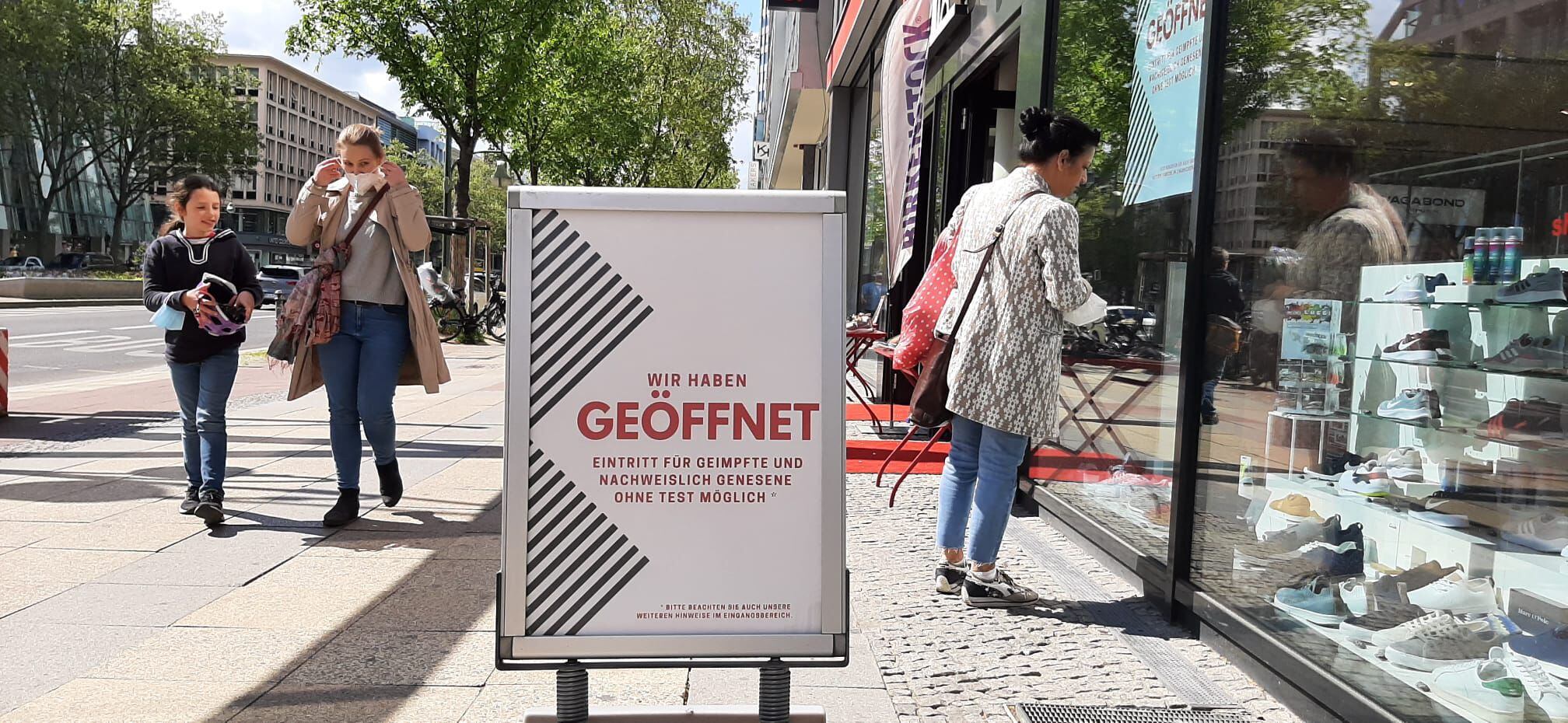 Loja de sapatos numa rua comercial de Berlim exibe cartaz dizendo que pessoas imunizadas podem entrar sem mostrar exame negativo.