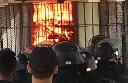 Policiais observam corredor de presídio CPPL IV em chamas durante rebelião.