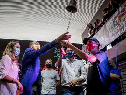 Convidados tocam o sino simbólico para celebrar a entrada da empresa Favela Brasil Express no mercado financeiro, em Paraisópolis, São Paulo.