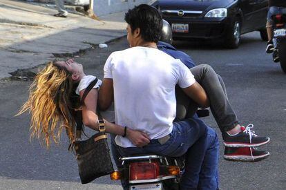 Genesis Carmona é levada em uma moto depois de ser atingida por um tiro.