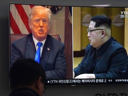 Um homem olha imagem de Trump e Kim na televisão.