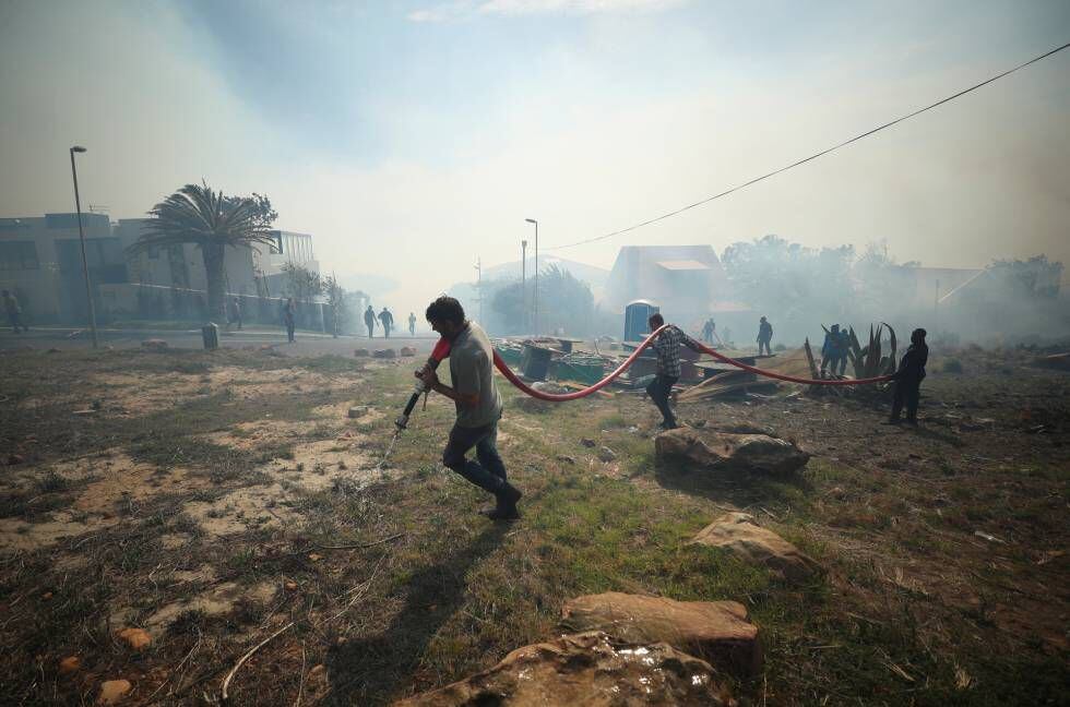 Moradores e bombeiros voluntários lutam para conter um incêndio, atiçado por fortes ventos, nas encostas da Table Mountain, na Cidade do Cabo.