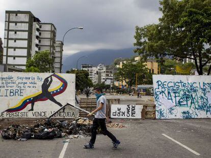 Jovem caminha em frente a uma barricada em Caracas.