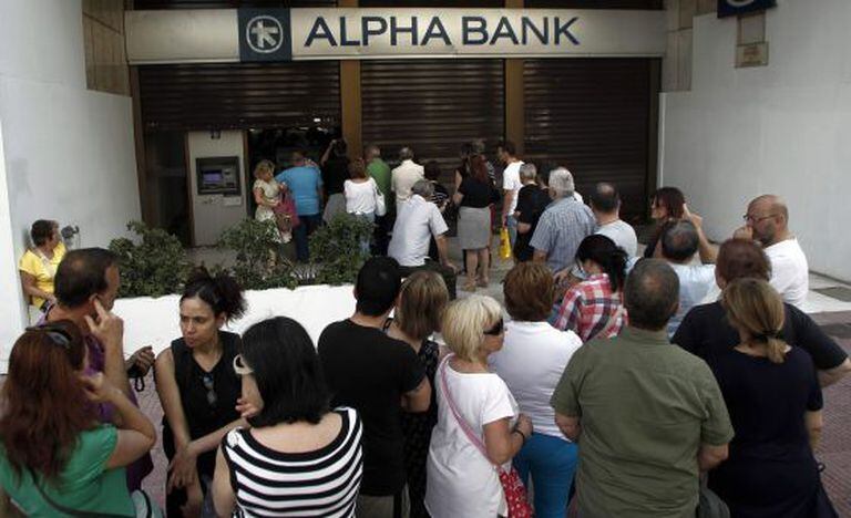 Atenienses fazem fila em frente a um caixa.