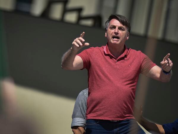 Brazil's President Jair Bolsonaro speaks to supporters during a protest asking for military intervention in front the army's headquarters during the new coronavirus pandemic, in Brasilia, Brazil, Sunday, April 19, 2020. Bolsonaro came out in support of a small protest Sunday that defended military intervention, infringing his own ministry's recommendations to maintain social distancing and prompting fierce critics. (AP Photo/Andre Borges)