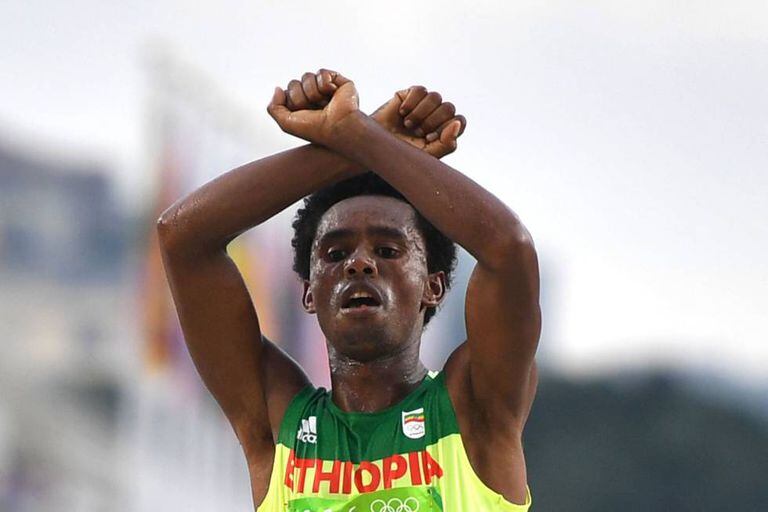 Feyisa Lilesa faz o gesto crítico ao cruzar a linha de chegada.