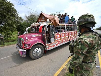 Indígenas colombianos a bordo de um ônibus ‘chiva’ passam diante de uma tropa militar nos arredores de Cali, na quarta-feira. Em vídeo, a participação dos indígenas nas manifestações.