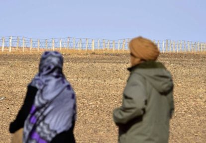 Duas pessoas contemplam a cerca que separa as zonas controladas pelo Marrocos e a Frente Polisário no Saara Ocidental.