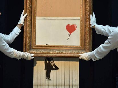 Empregados da Sotheby’s carregam a obra semidestruída de Banksy.