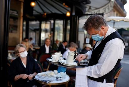 Garçom atende clientes em um café de Paris.