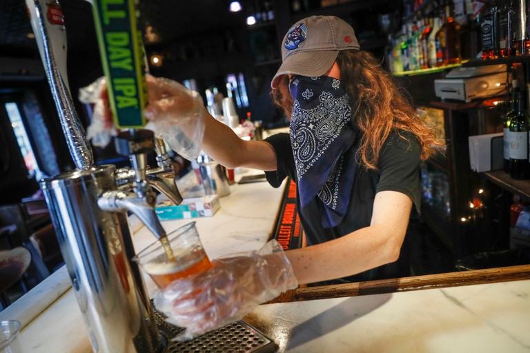 Garçonete serve uma cerveja em um bar de Nova York, em junho.