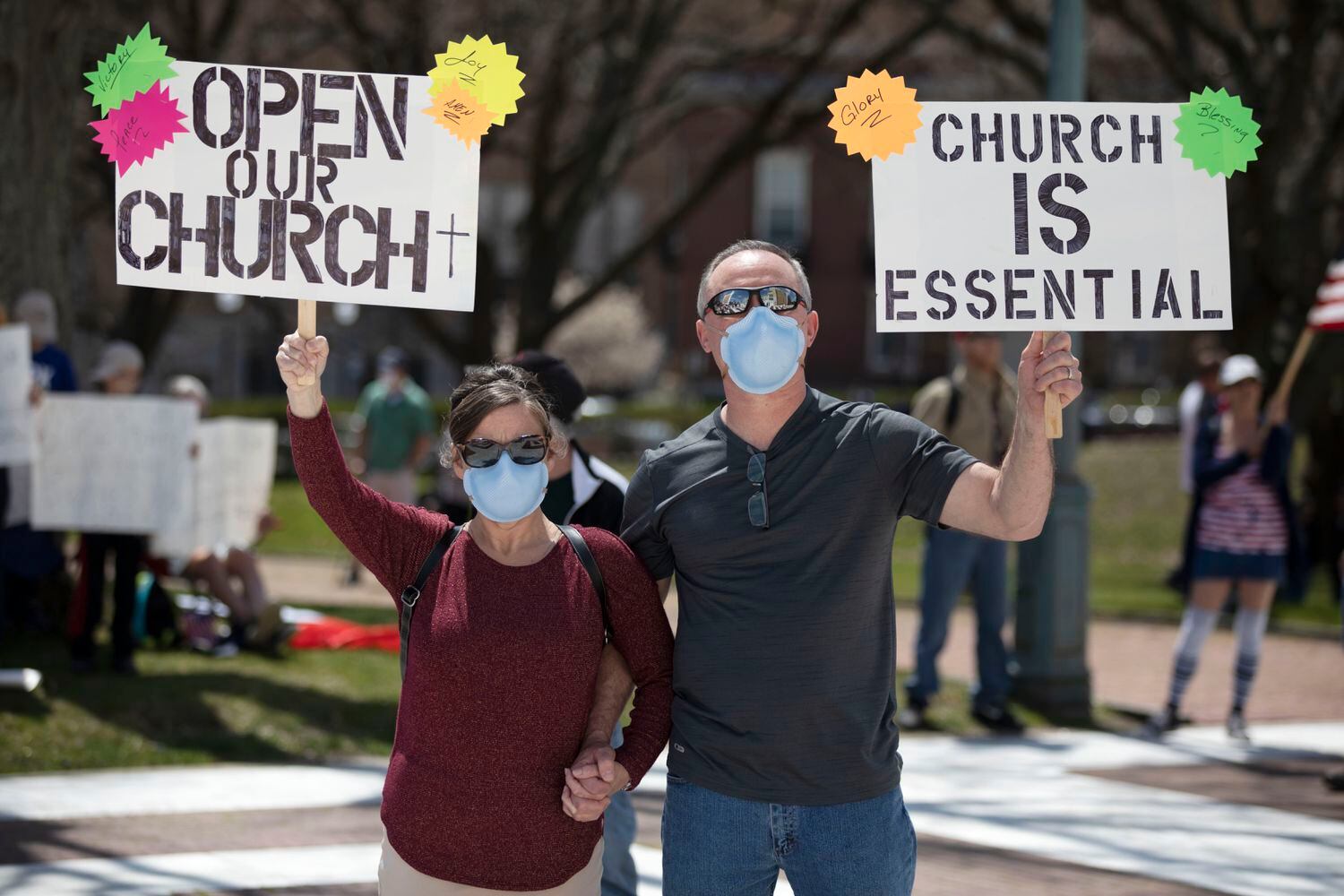 Com cartazes "Abram nossa igreja" e "Igreja é essencial", pessoas se manifestam contra as ordens de ficar em casa devido ao coronavírus neste sábado,  em Providence, nos EUA.